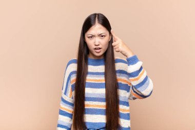 Asyalı genç bir kadın kızgın agresif bir ifadeyle kameraya bakıyor. Öfkeli, çılgın bir patron gibi görünüyor.