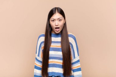 Asyalı genç kadın korkmuş ve şok olmuş hissediyor, ağzı açık şaşkınlık içinde.