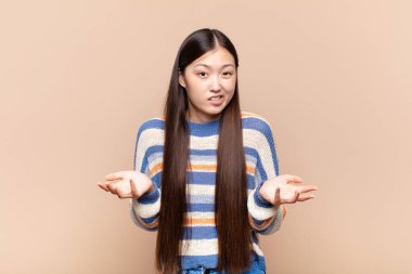 Asyalı genç bir kadın bilgisiz ve kafası karışık, hangi seçeneği seçeceğinden emin değil, merak ediyor.