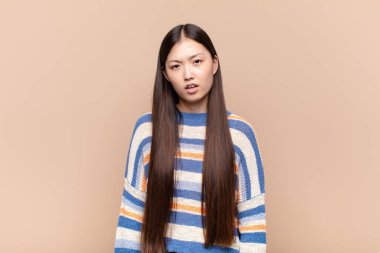asian young woman feeling puzzled and confused, with a dumb, stunned expression looking at something unexpected