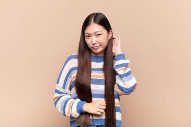 Asyalı genç bir kadın stresli, hayal kırıklığına uğramış ve yorgun hissediyor. Endişeli ve sorunlu bir bakışla boynunu ovalıyor.