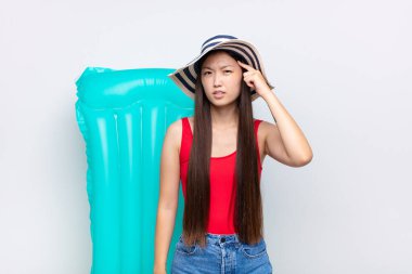 Asyalı genç bir kadın kafası karışık ve şaşkın hissediyor. Deli, deli ya da aklını kaçırmış olduğunu gösteriyor. yaz konsepti
