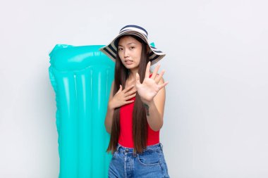 Asyalı genç bir kadın korku ve panik içinde geri çekilip çığlık atıyor ve bir kabusa tepki veriyor. yaz konsepti