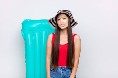 Asyalı genç kadın kendini cahil, kafası karışık ve hangi seçeneği seçeceği konusunda kararsız hissediyor. Sorunu çözmeye çalışıyor. yaz konsepti