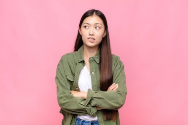 Asyalı genç bir kadın kuşkulanıyor ya da düşünüyor, dudağını ısırıyor ve kendini güvensiz ve gergin hissediyor.