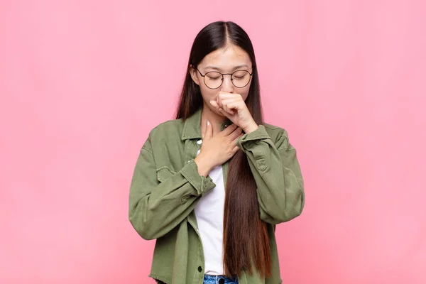 アジア系の若い女性は喉の痛みやインフルエンザの症状を感じ口を覆い咳をし — ストック写真