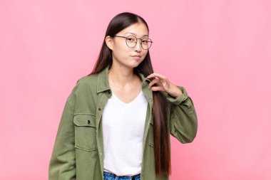 Asyalı genç bir kadın kibirli, başarılı, pozitif ve gururlu görünüyor.