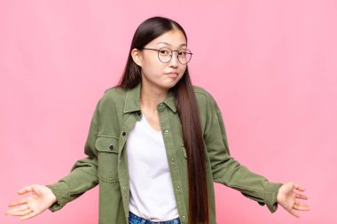 asian young woman feeling clueless and confused, having no idea, absolutely puzzled with a dumb or foolish look