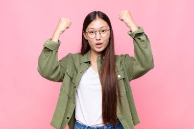 Asyalı genç bir kadın inanılmaz bir başarıyı kutluyor. Kazanan gibi. Heyecanlı ve mutlu görünüyor.!