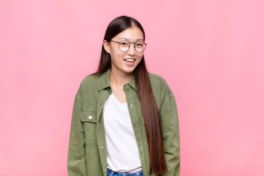 Asyalı genç bir kadın, büyük, dost canlısı, kaygısız bir gülümsemesi var, pozitif, rahat ve mutlu görünüyor, ürpertici.