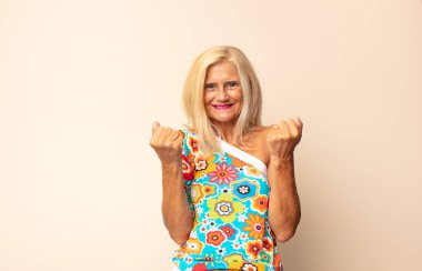 Orta yaşlı kadın zaferle bağırıyor, gülüyor, mutlu ve heyecanlı hissediyor başarıyı kutlarken.