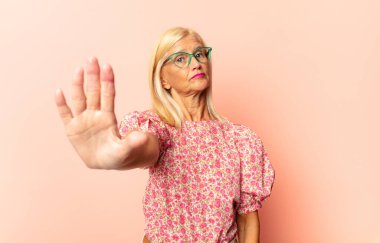 Orta yaşlı bir kadın ciddi, sert, hoşnutsuz ve kızgın görünüyor.