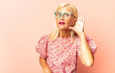 Orta yaşlı kadın şaşkınlık ve şaşkınlık içinde bakıyor. Alnı açık, uzaklara bakıyor, izliyor ya da arıyor.