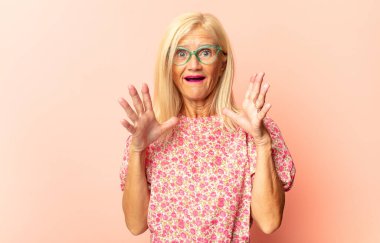 Orta yaşlı bir kadın şok olmuş, kızgın, sinirli ya da hayal kırıklığına uğramış, ağzı açık ve öfkeli görünüyor.