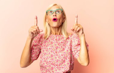 Orta yaşlı bir kadın romantik, mutlu ve aşık, neşeli bir şekilde gülümseyen ve kalbe yakın el ele tutuşan