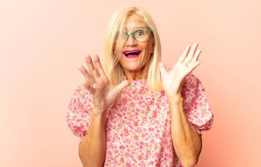 Orta yaşlı bir kadın elleri havada bağırıyor. Öfkeli, sinirli, stresli ve üzgün.