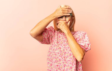 Orta yaşlı bir kadın şaşkın ve şaşırmış hissediyor. Şaşırmış ve ağzı açık bir şekilde hayranlıkla yukarı bakıyor.