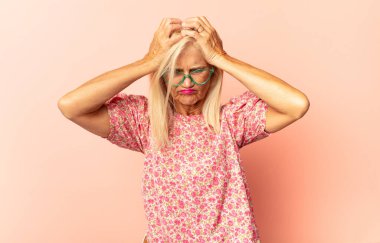 Orta yaşlı bir kadın stresli, hayal kırıklığına uğramış ve yorgun, endişeli ve sorunlu bir bakışla boynunu ovalıyor.