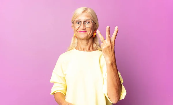 Жінка Середнього Віку Посміхається Виглядає Доброзичливою Показуючи Номер Три Або — стокове фото
