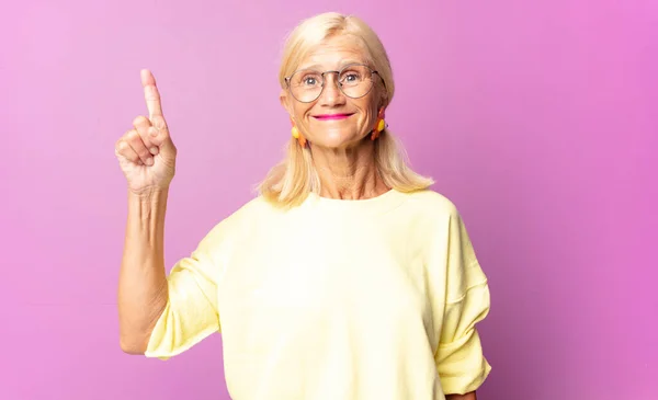 Medelålders Kvinna Ler Glatt Och Glatt Pekar Uppåt Med Hand — Stockfoto