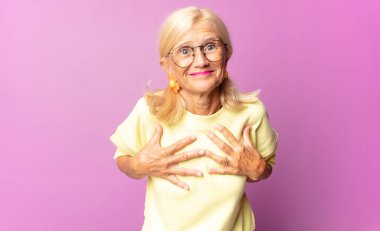 Orta yaşlı kadın mutlu, şaşırmış, gururlu ve heyecanlı görünüyor.