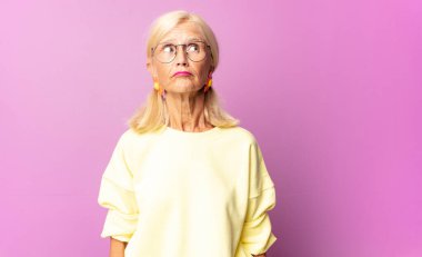 Orta yaşlı kadın merak ediyor, mutlu düşünceler ve fikirler düşünüyor, hayal kuruyor, kenarda yer arıyor.