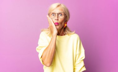 Orta yaşlı bir kadın ağzı açık bir şekilde yüz yüze inanmayarak şok olmuş ve hayrete düşmüş hissediyor.