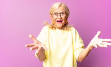 Orta yaşlı bir kadın son derece şok olmuş, şaşırmış, endişeli ve paniklemiş, stresli ve dehşete kapılmış bir şekilde bakıyor.