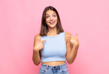 Genç, güzel bir kadın mutlu, şaşırmış ve gururlu hissediyor. Heyecanlı ve şaşkın bir bakışla kendini işaret ediyor.