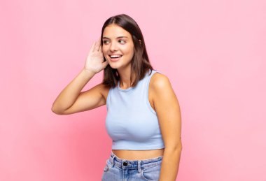 Genç, güzel bir kadın gülümsüyor, tuhaf bir şekilde yan tarafa bakıyor, dedikoduları dinlemeye ya da bir sırrı duymaya çalışıyor.