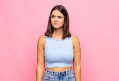 Genç, güzel bir kadın üzgün, üzgün ya da kızgın ve olumsuz bir tavır takınıyor, anlaşmazlık içinde kaşlarını çatıyor.