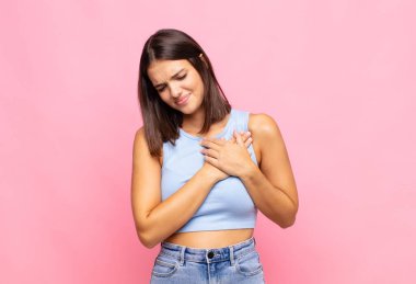 Genç, güzel bir kadın üzgün, yaralı ve kalbi kırık görünüyor, iki elini de kalbine yakın tutuyor, ağlıyor ve bunalımda.