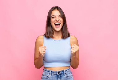 Genç, güzel bir kadın sinirli, sinirli, kızgın bakışlar ve sıkı yumruklar ile agresif bir şekilde bağırıyor.