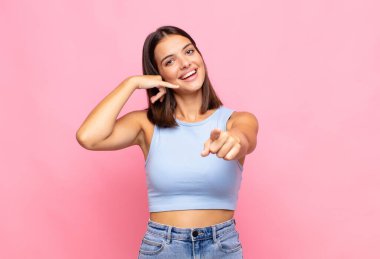 Genç, güzel bir kadın neşeyle gülümsüyor ve kamerayı işaret ediyor. Sonra seni arıyor, telefonla konuşuyor.