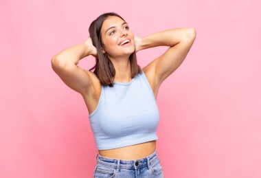 Genç ve güzel bir kadın gülümsüyor ve rahatlıyor, tatmin oluyor ve kaygısız, neşeli ve rahatlatıcı.