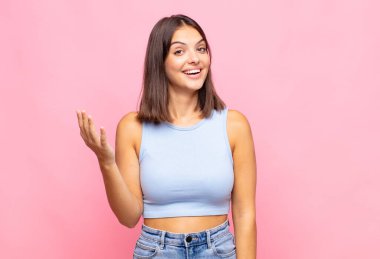 Genç, güzel bir kadın kendini mutlu, şaşırmış ve neşeli hissediyor. Pozitif bir tavırla gülümsüyor. Bir çözüm ya da fikir buluyor.