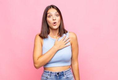 Genç ve güzel bir kadın şok olmuş ve şaşırmış hissediyor, gülümsüyor, el ele tutuşuyor, o kişi olmaktan mutlu ya da minnettarlık gösteriyor.