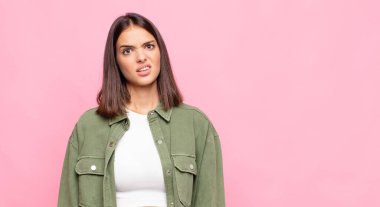 Genç, güzel bir kadın şaşkın ve şaşkın hissediyor, aptal, sersemlemiş bir ifadeyle beklenmedik bir şeye bakıyor.