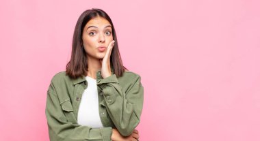 Genç, güzel bir kadın, ağzı açık bir şekilde yüz yüze inanmayarak şok olmuş ve hayrete düşmüş hissediyor.