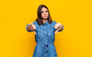 Genç, güzel bir kadın üzgün, hayal kırıklığına uğramış ya da kızgın görünüyor. Anlaşmazlıkta baş parmaklarını gösteriyor. Hayal kırıklığına uğramış hissediyor.