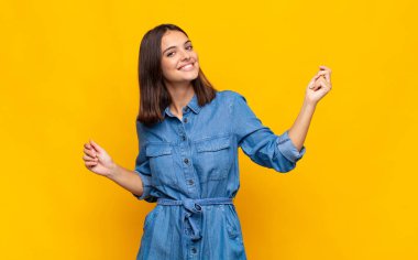 Genç, güzel bir kadın gülümsüyor, kaygısız hissediyor, rahat ve mutlu, dans ediyor ve müzik dinliyor, bir partide eğleniyor.