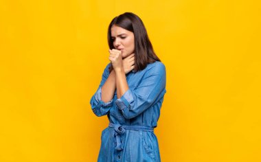 Gırtlağı ağrıyan ve grip belirtileri gösteren, ağzı kapalı öksüren genç ve güzel bir kadın.