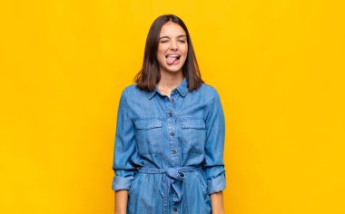 Neşeli, kaygısız, asi tavrıyla genç, güzel bir kadın şakalaşıyor ve dillerini çıkarıp eğleniyor.