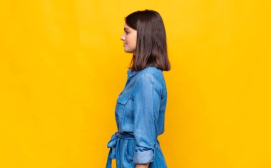 Profil görünümünde genç ve güzel bir kadın ilerideki boşluğu kopyalamaya çalışıyor, düşünüyor, hayal ediyor ya da hayal kuruyor.