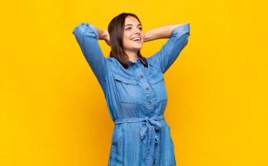 Genç ve güzel bir kadın gülümsüyor ve rahatlıyor, tatmin oluyor ve kaygısız, neşeli ve rahatlatıcı.