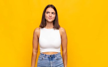 Genç ve güzel bir kadın kafası karışmış görünüyor, merak ediyor veya bir sorunu çözmeye çalışıyor ya da düşünüyor.