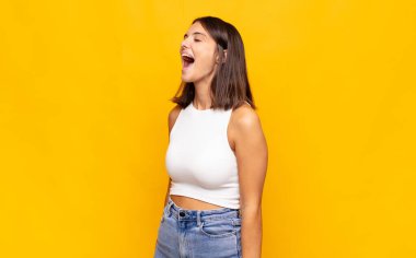 Genç ve güzel bir kadın öfkeyle bağırıyor, agresif bir şekilde bağırıyor, stresli ve kızgın görünüyor.