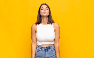 Genç, güzel bir kadın dudaklarını birbirine bastırıyor. Sevimli, eğlenceli, mutlu, sevimli bir yüz ifadesiyle. Öpücük yolluyor.