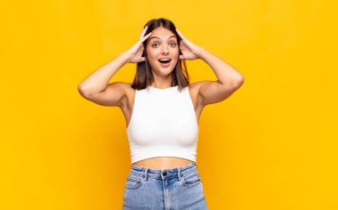 Genç ve güzel bir kadın el ele tutuşuyor, ağzı açık, son derece şanslı, şaşırmış, heyecanlı ve mutlu hissediyor.