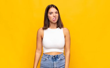 Genç ve güzel bir kadın, tiksinmiş ve rahatsız olmuş hissediyor. Dilini dışarı çıkarıyor, iğrenç ve iğrenç bir şeyden hoşlanmıyor.